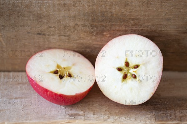 Cut apple on a wooden plank, showing the seeds in a delicate five pointed star motive