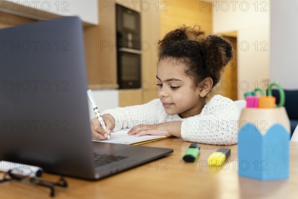 Little girl home studying during online school with laptop