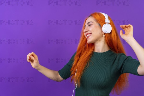 Redhead woman in studio photography dancing on a purple background
