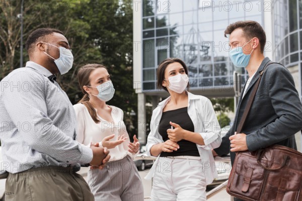 Colleagues chatting outdoors during pandemic with face masks