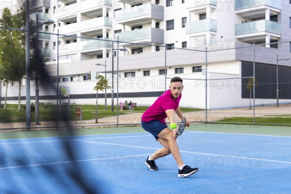 Man playing pickleball game, hitting pickleball ball with paddle, outdoor sport leisure activity