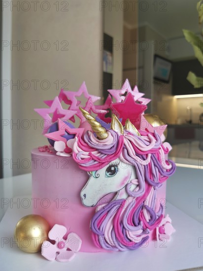 A whimsical unicorn birthday cake with pink and gold decorations, featuring pastel flowers and star