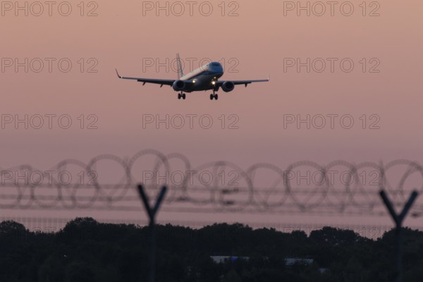 Passenger aircraft Embraer ERJ-190STD Cityhopper of the airline KLM in the sunset approaching