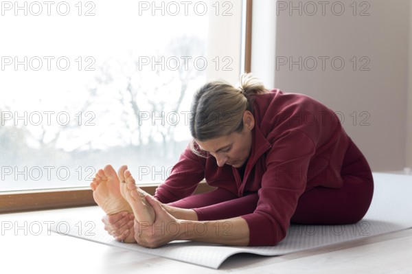 Mature woman doing sport exercises her window