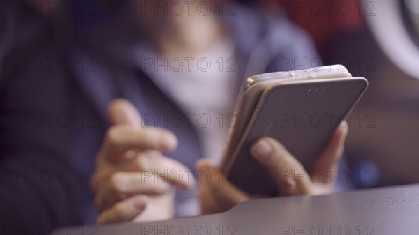 Close-up of the hands of an elderly woman sitting in a train carriageriage and using a smartphone