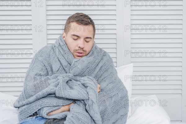 Young man wrapped warm scarf shivering from cold