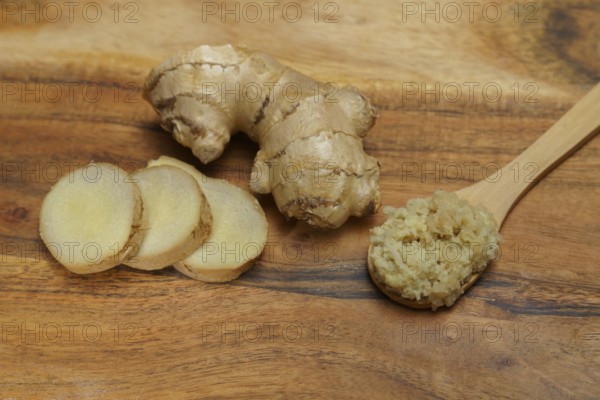 Ground ginger in a wooden spoon with fresh ginger root cut in slices