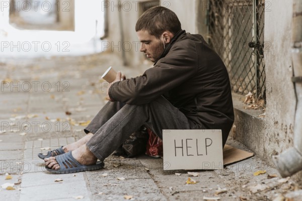 Homeless man street with cup help sign