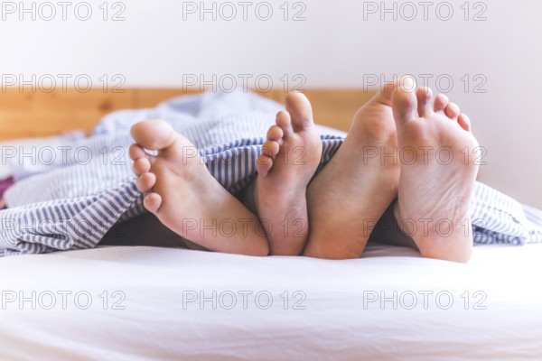 Close up a couples uncovered feet sleeping in bed, morning