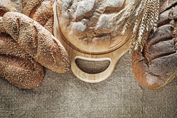Black bread breadstick cutting board wheat ears on hessian background