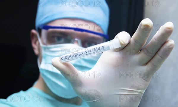 A scientist holds in his hand a test tube with the virus coronavirus
