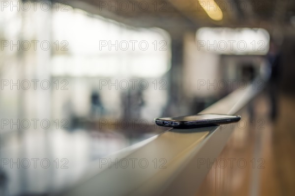 A smartphone lies on a railing