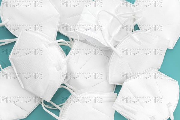 Group of used KN95 face mask on turquoise table. Coronavirus Covid-19 disposable masks wasting