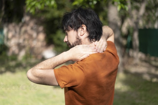 Latin man massages his neck. Sportsman with neck pain massages himself