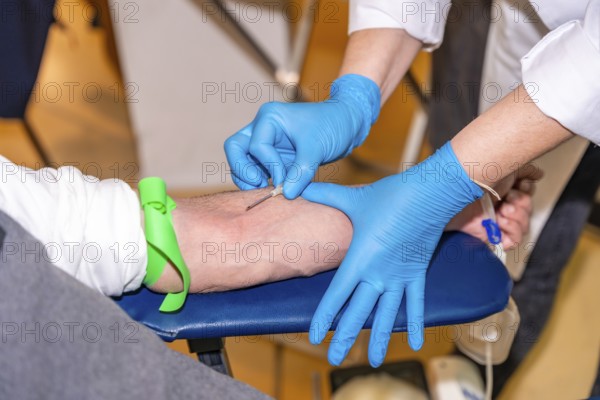 Close-up of an unrecognizable nurse puncturing the vein of a blood donor