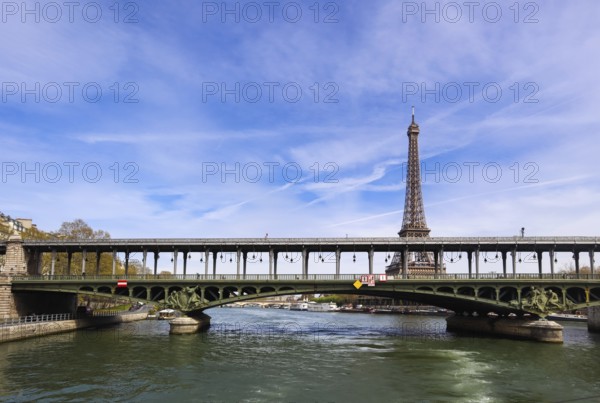 Eiffel Tower against blue sky with clouds and a bridge Pont de Bir-Hakeim (pont de Passy) over