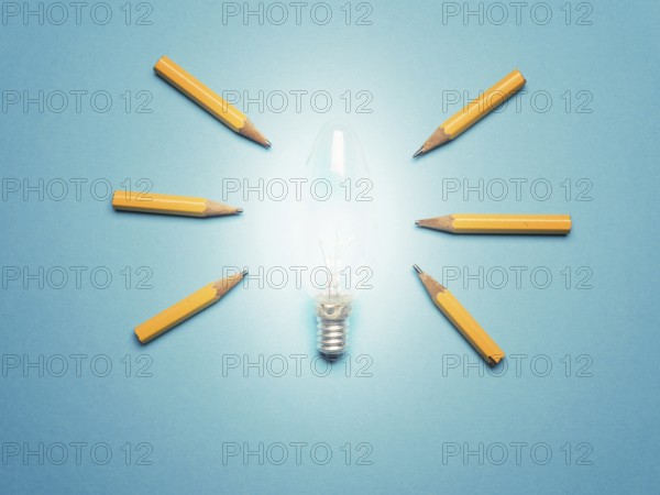 A glowing light bulb with 6 pencils as light rays, New ideas or creativity concept on blue