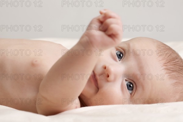 Ten weeks old cute little baby girl toddler with curious look on her face lying comfortably on bed