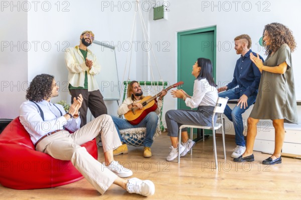 Distracted people singing and playing guitar during a break in a coworking