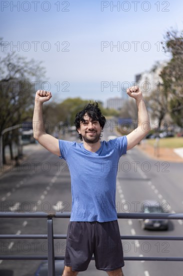 Successful man raising arms after running. Fitness male athlete with arms up celebrating success