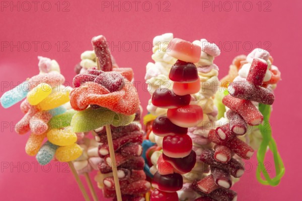 Variation of colorful fruit gums sweets skewered sour gummy bears on wooden skewers isolated on a
