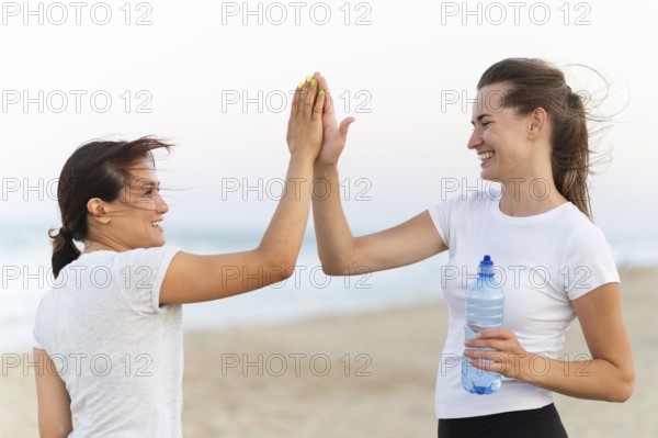Side view two women high fiving each