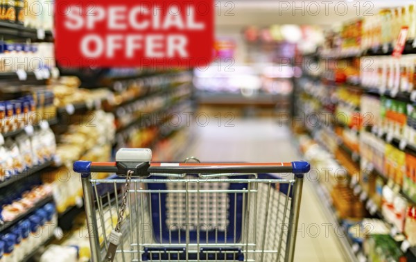 A shopping cart by a store shelf in a supermarket