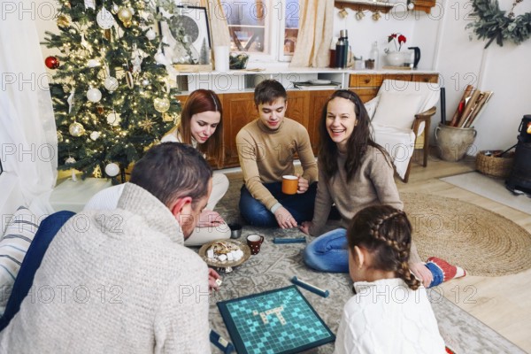 Big family sitting on floor playing intellectual board games together while spending leisure time