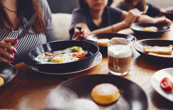 Hands taking pastries, vegetables, greens, cheeses, fried eggs, jams and tea in copper pot and