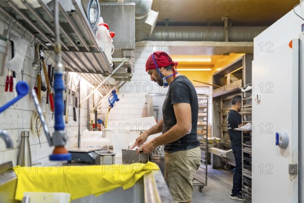 Male baker of bakery in the workshop of artisan bakery preparing the sourdoughs