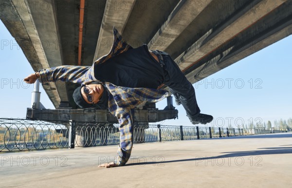 Young man break dancer dancing on urban background performing acrobatic stunts. Street artist