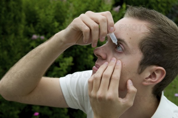 Young man takes eye drops, allergy, pollen allergy