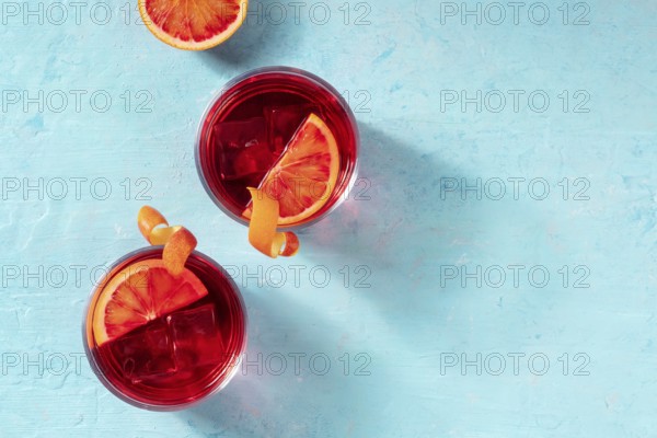 Negroni cocktails decorated with blood oranges, top shot on a blue background with a place for text