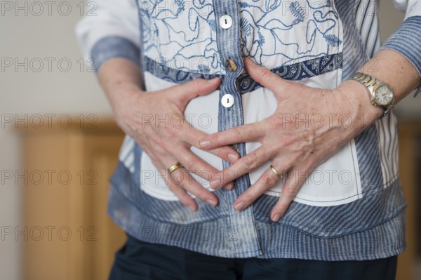 A woman's hands clasped in front of her stomach