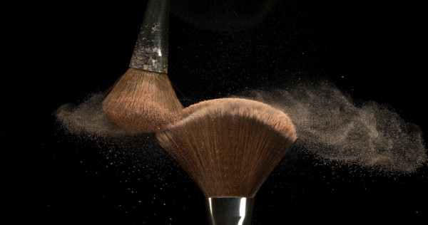 Make-up Brush spreading blush powder on black background