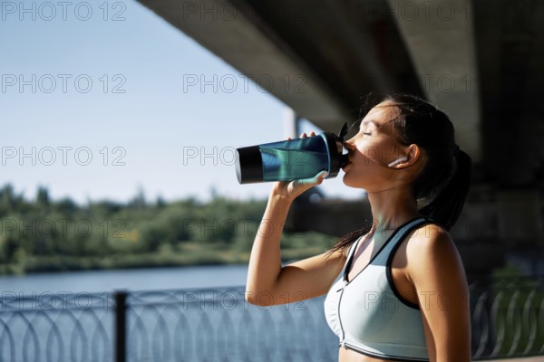 Young fitness woman drinking water from bottle. Sporty female resting after work out exercising in