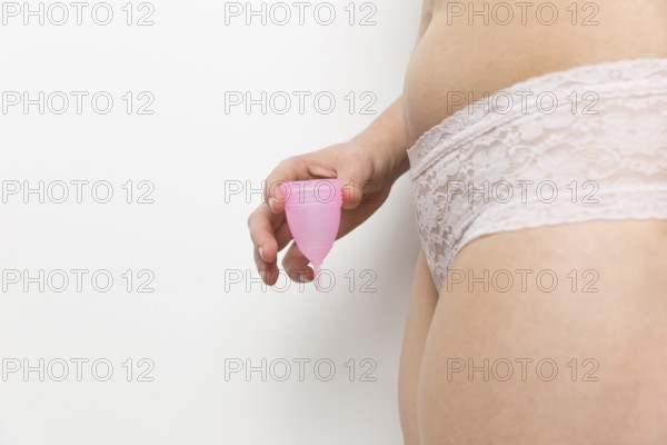 Woman sideways panties holding menstrual cup