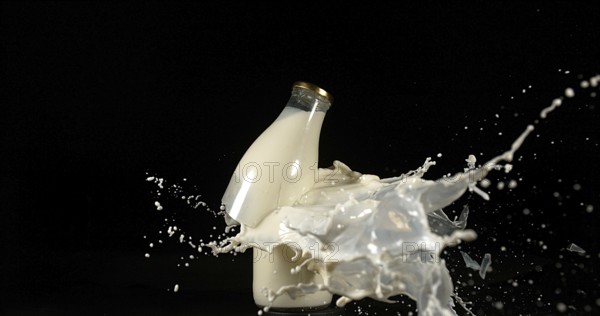 Bottle of Milk Exploding against Black Background