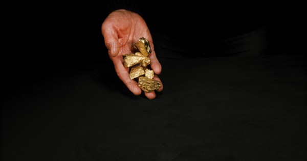 Hand and Gold Nuggets, Nugget, Falling on Black Background