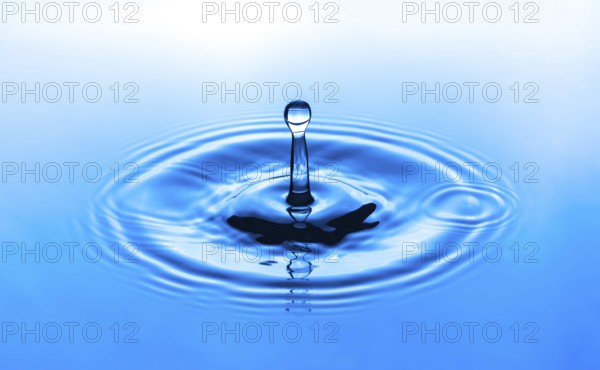 Water drop splashing into blue water surface. Health and purity concept
