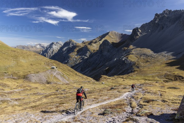 Alp Ramoz with Ramozhütte SAC, mountain biker on a trail, view into Welschtobel, behind Davos Alps