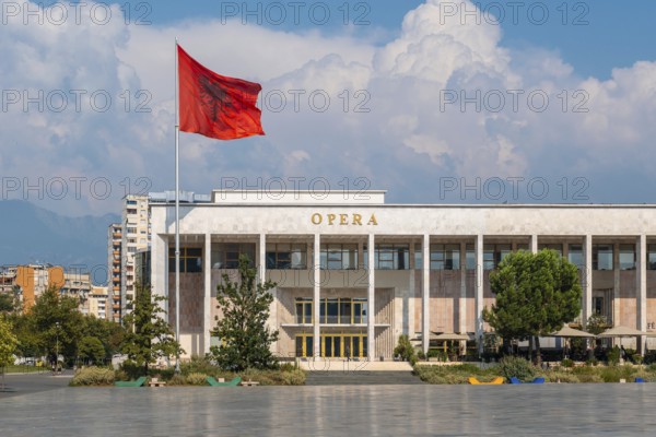 Palace of Culture or Opera on Skanderbeg Square in Tirana and the flag of Albania moving in the