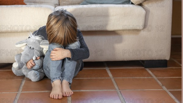Little boy outdoors upset holding his toy