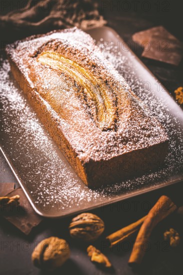 Homemade vegan banana bread or cake with nuts, chocolate and cinnamon on brown background