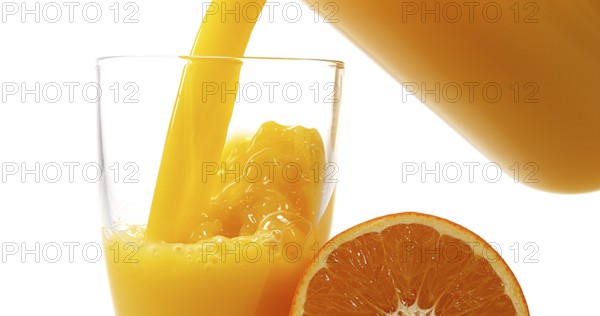 Orange Juice being poured into Glass against White Background