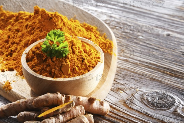 Composition with a bowl of ground turmeric and its fresh rhizome