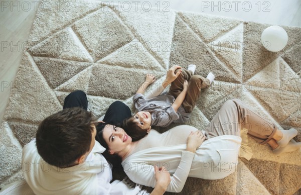 View from above of happy family with small kid expecting new baby. Pregnant mother, father and