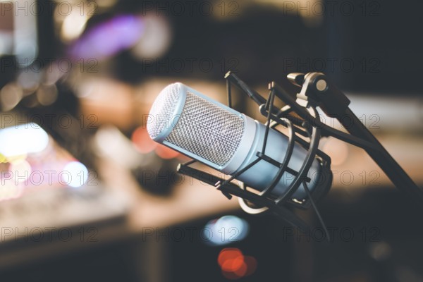 Microphone in a professional recording or radio studio, equipment in the blurry background