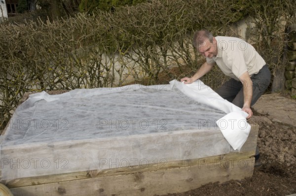 Man covers raised bed with fleece, mound bed, sowing, sowing, seeding