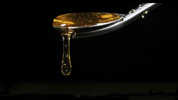 Honey Flowing from Spoon against Black Background